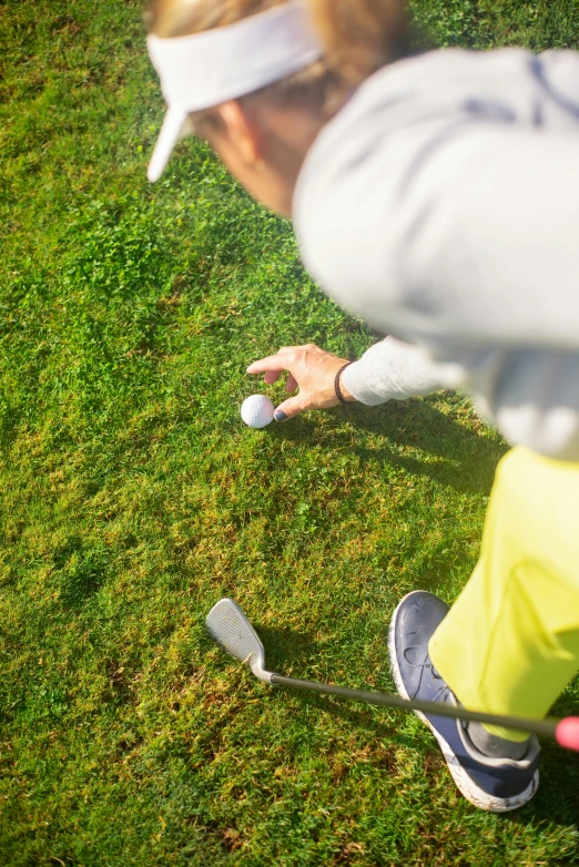 a man holding a golf club on top of a lush green field, head straight down, sports setting, swoosh, grey