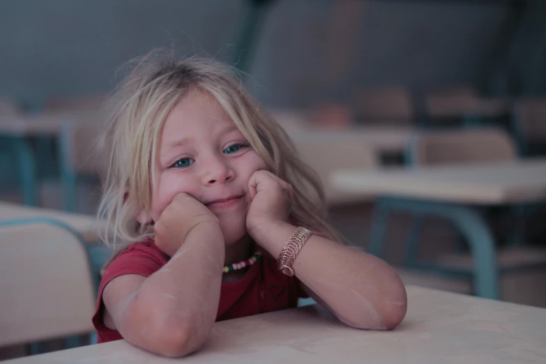 a little girl sitting at a table in a classroom, pexels contest winner, danube school, satisfied pose, teaser, thoughtful )