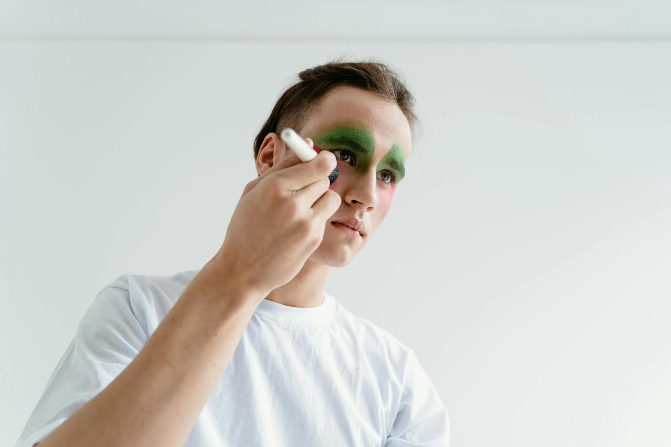 a man holding a toothbrush in front of his face, a hyperrealistic painting, by Julia Pishtar, trending on pexels, dark green smokey eyeshadow, putting makeup on, on a white table, lachlan bailey