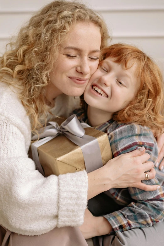 a woman hugging a little girl who is holding a present, square, ( redhead, 15081959 21121991 01012000 4k, teen boy