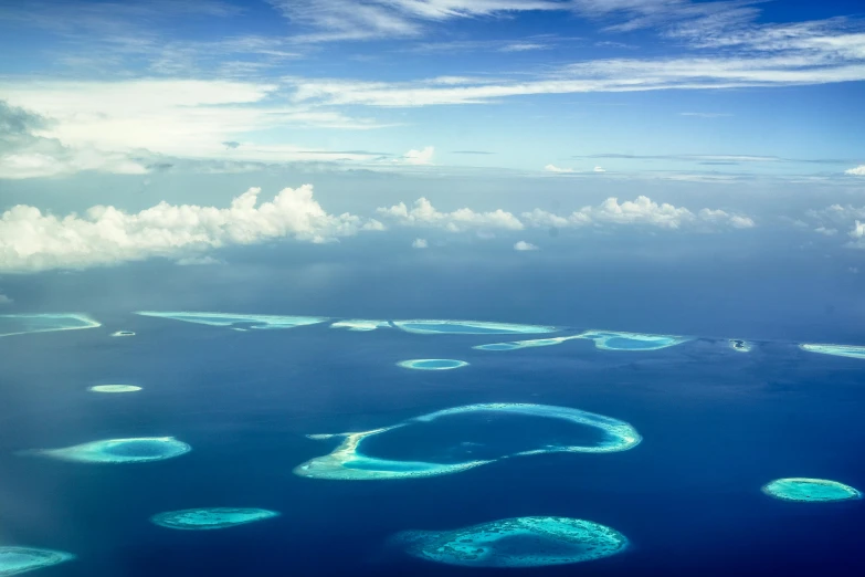 a group of small islands in the middle of the ocean, by Peter Churcher, pexels contest winner, hurufiyya, open skies, maldives in background, endless loop, national geograpic