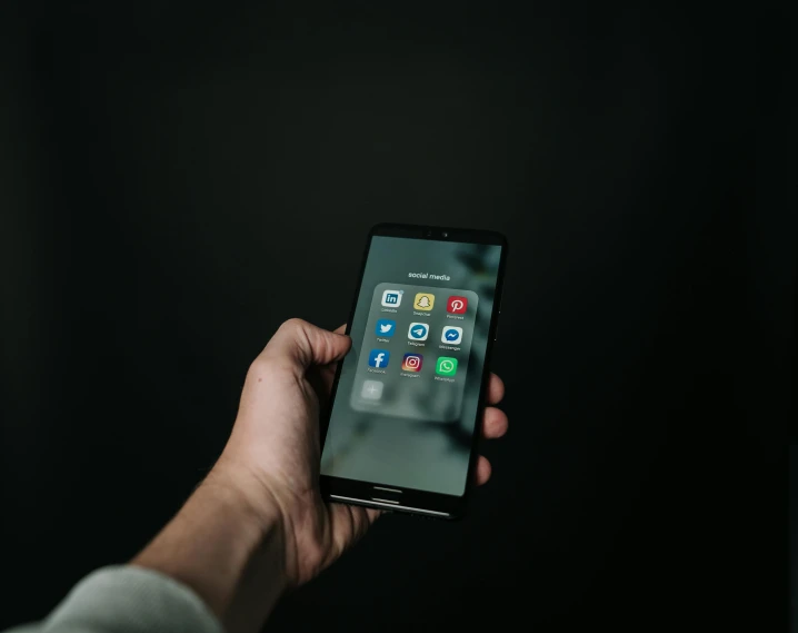 a person holding a smart phone in their hand, trending on pexels, dark theme, logo for a social network, droid, 4800k