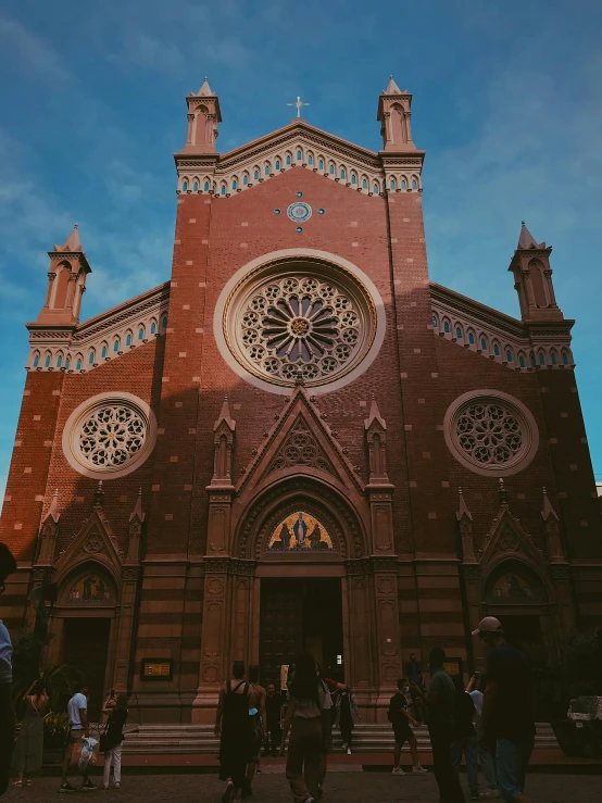 a group of people standing in front of a church, inspired by Modest Urgell, pexels contest winner, art nouveau, buenos aires, brown, symmetrical front view, red building