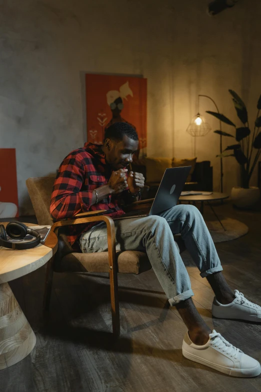 a man sitting in a chair using a laptop, pexels contest winner, happening, ( ( dark skin ) ), sitting in a lounge, having a snack, young male