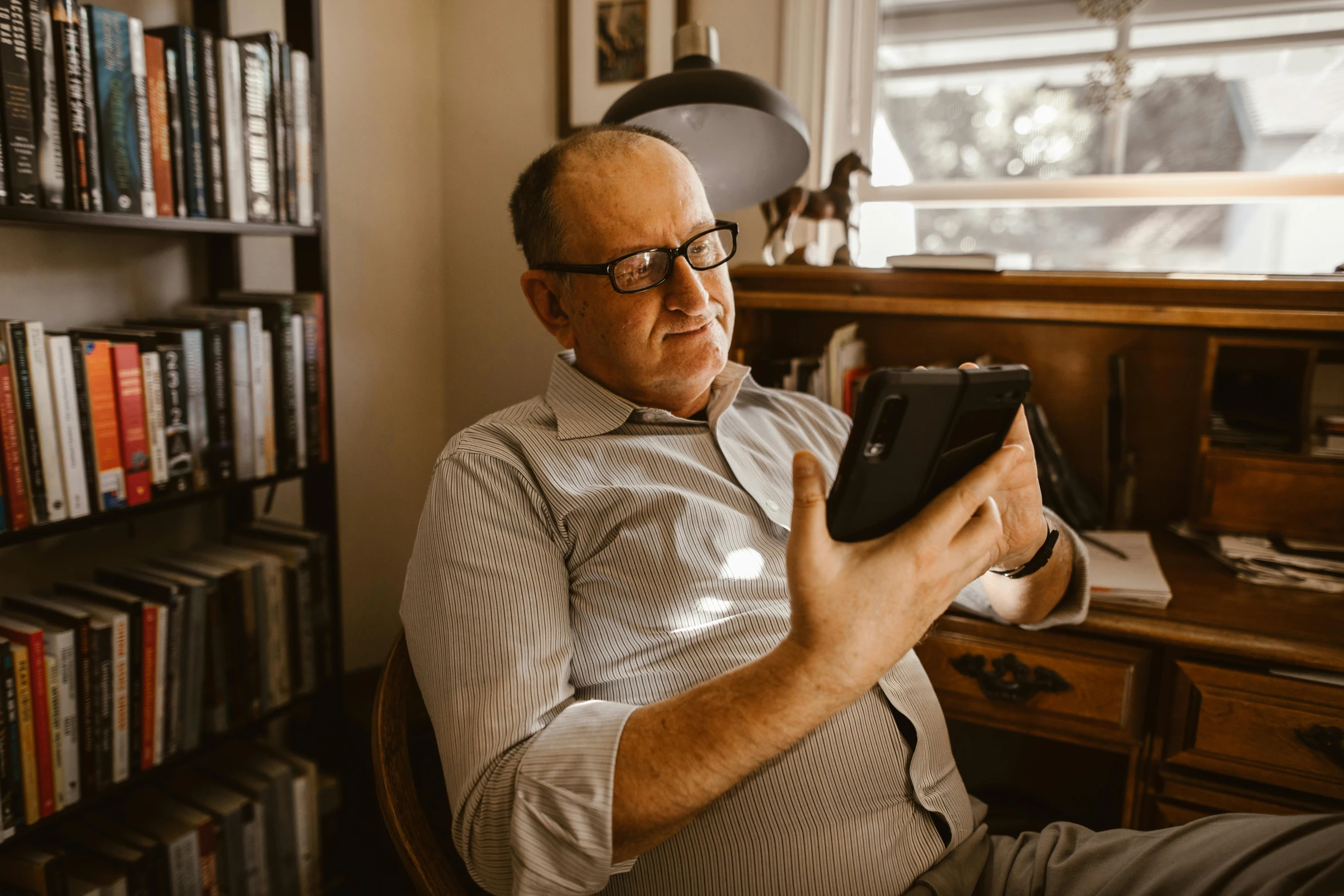 a man sitting in a chair holding a tablet computer, a portrait, by Will Ellis, pexels contest winner, happening, wearing reading glasses, australian, at home, thumbnail
