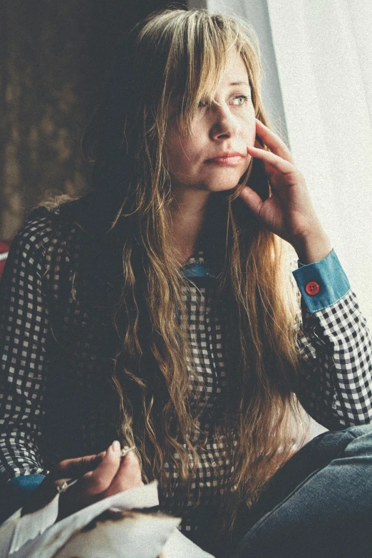 a woman sitting in front of a window talking on a cell phone, a picture, inspired by Elsa Bleda, pexels, renaissance, long hair and red shirt, portrait of depressed teen, hippie, corduroy