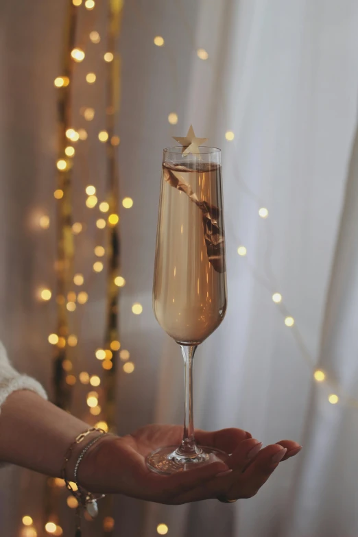 a close up of a person holding a glass of wine, with stars, ivory and copper, slim, decorations