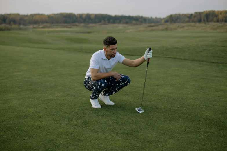 a man kneeling on top of a green field holding a golf club, a portrait, by Matija Jama, pexels contest winner, wearing only pants, avatar image, patterned clothing, high quality image