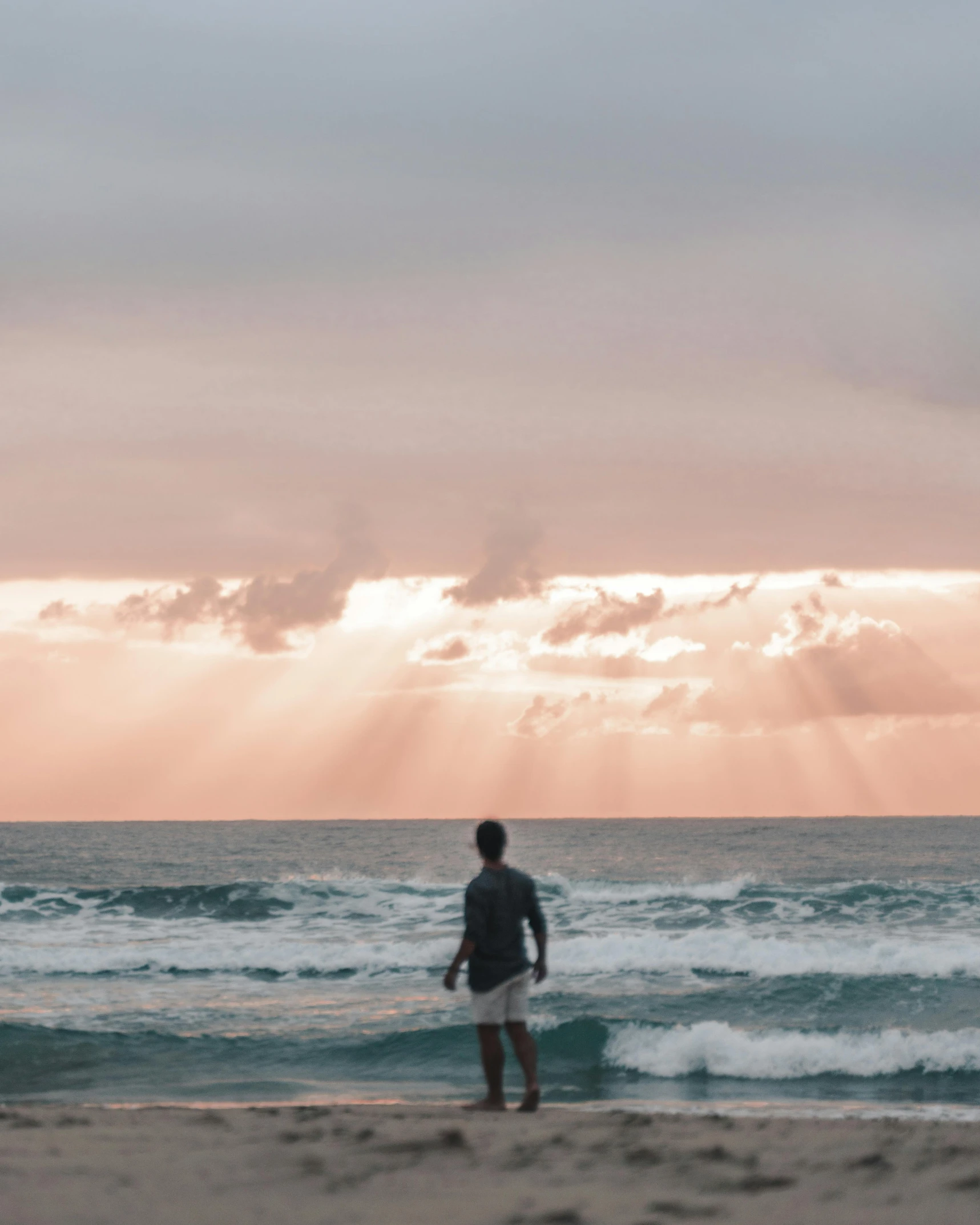 a man standing on top of a beach next to the ocean, lgbtq, god rays!!!, trending on vsco, gold coast australia