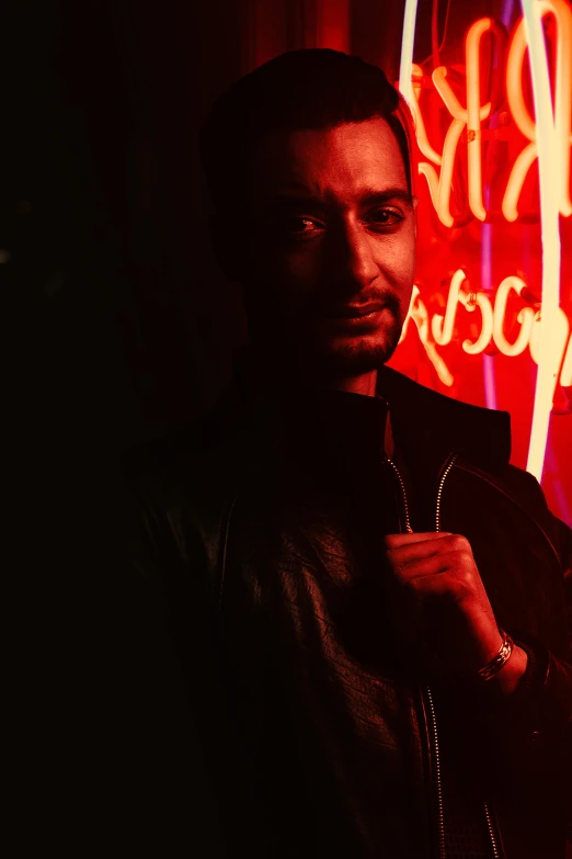 a man standing in front of a neon sign, inspired by Nan Goldin, reddit, serial art, nipsey hussle, seductive smirk, profile image, ( ( theatrical ) )
