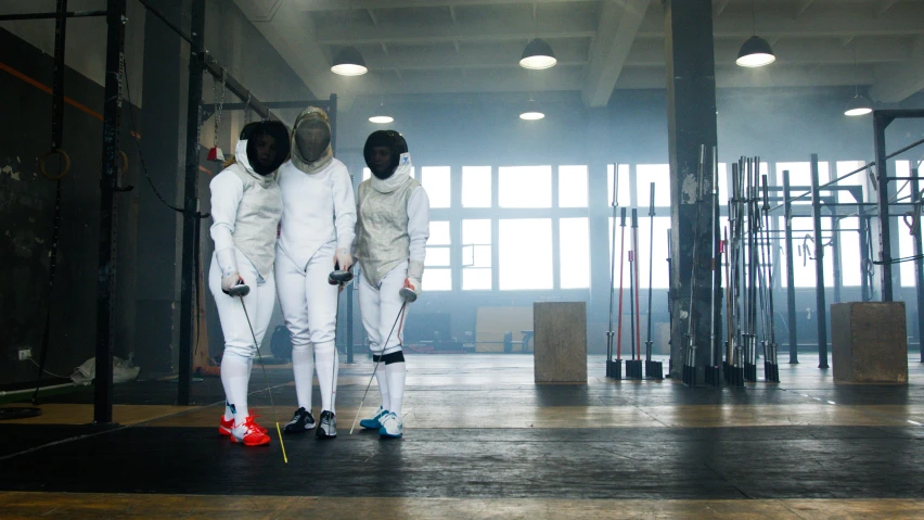 a group of fencers standing next to each other, pexels contest winner, happening, 2 techwear women, filmstill, wired, indoor