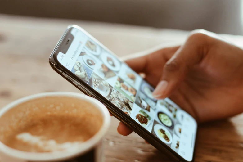 a person holding a cell phone next to a cup of coffee, a picture, trending on pexels, happening, brown, avatar image, instagram digital, eating
