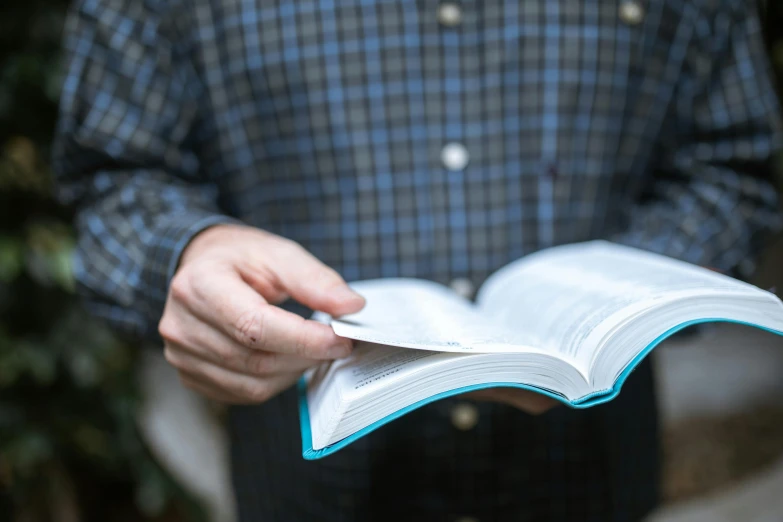 a close up of a person holding an open book, paul barson, salvation, college, photo of a man