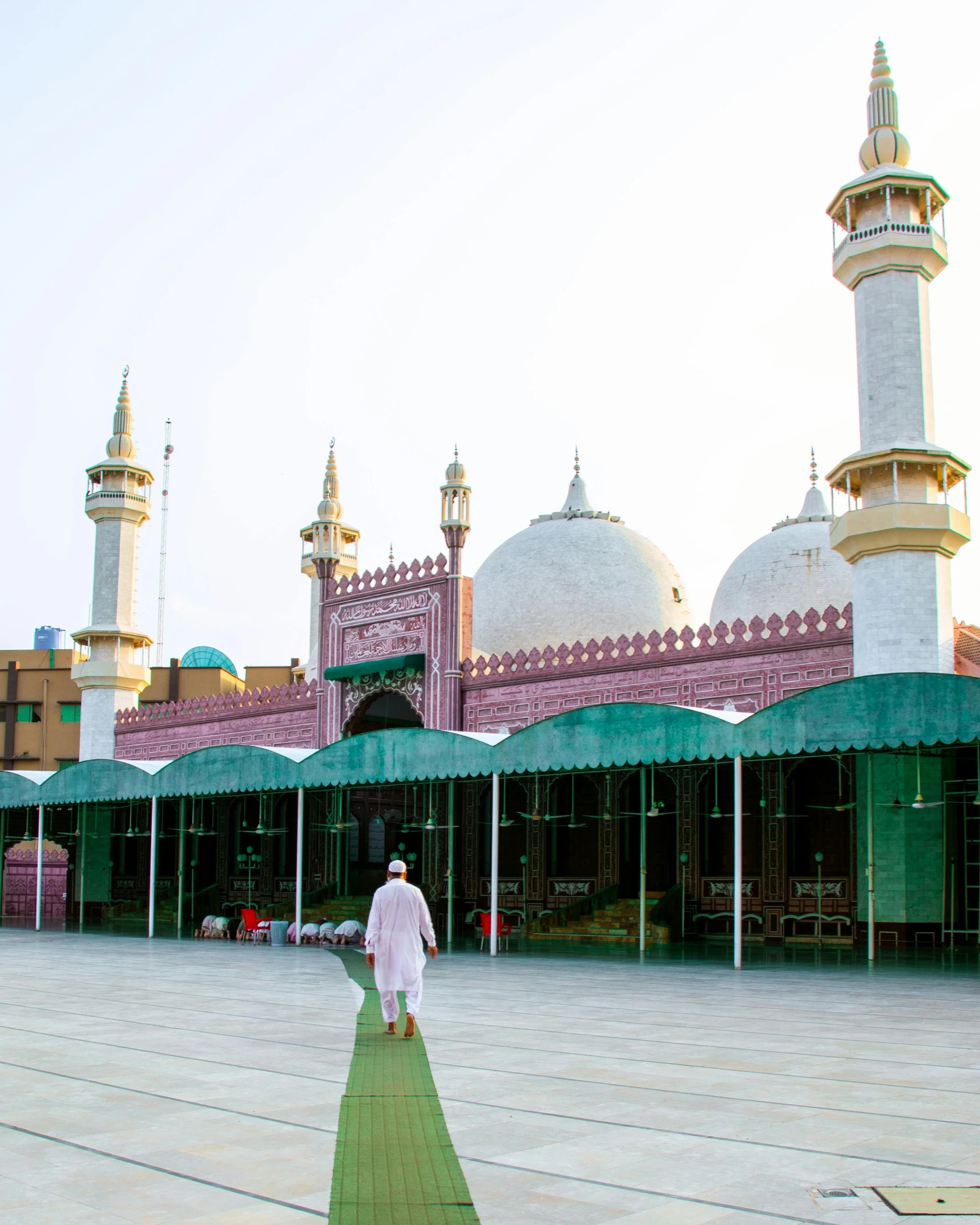 a man is walking in front of a mosque, a colorized photo, pexels contest winner, pink white and green, completely empty, trending on, mogul khan