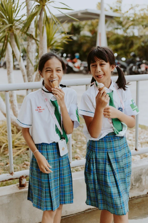 a couple of young girls standing next to each other, pexels contest winner, sumatraism, uniform teeth, having a snack, promo image, multiple stories