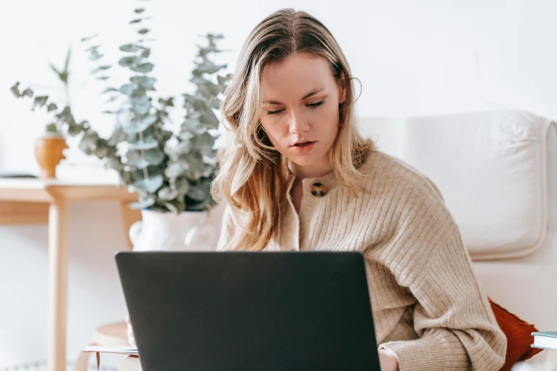 a woman sitting on a couch using a laptop, a portrait, trending on pexels, close up of a blonde woman, avatar image, woman with braided brown hair, working hard