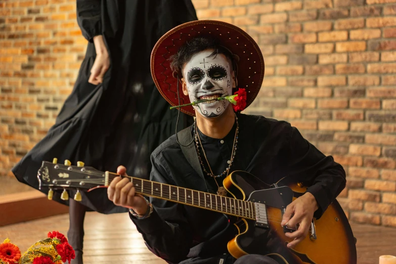 a man that is sitting down with a guitar, by Alejandro Obregón, pexels contest winner, vanitas, face painting, full shot, thumbnail, holiday season