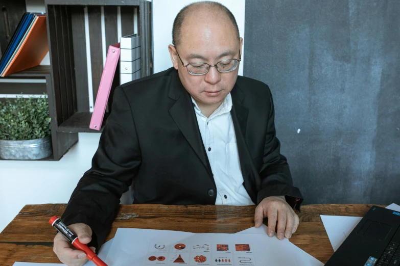 a man sitting at a table with a pen and paper, a cartoon, inspired by Fei Danxu, with dong son bronze artifacts, academy headmaster, most respected design, on a white table