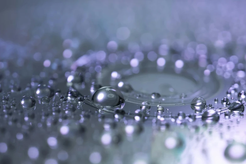 a close up of water droplets on a surface, inspired by Perle Fine, glittering silver ornaments, some purple and blue, silver iodide