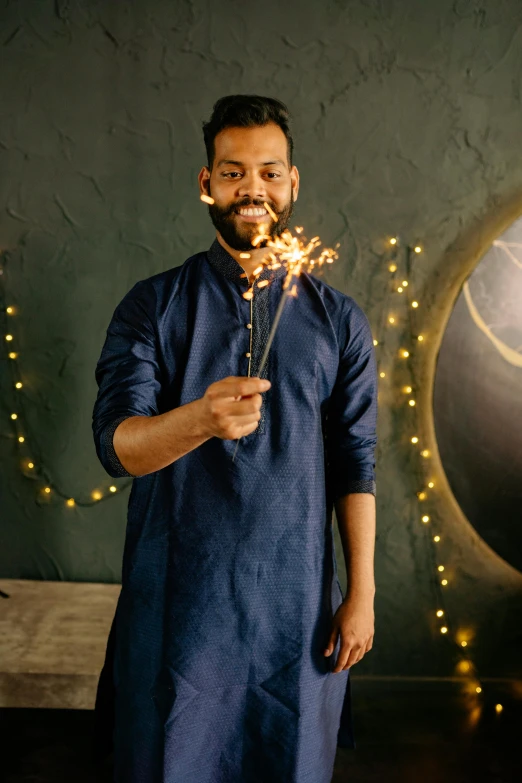 a man holding a sparkler in front of a globe, wearing a silk kurta, navy, wearing festive clothing, wearing a linen shirt