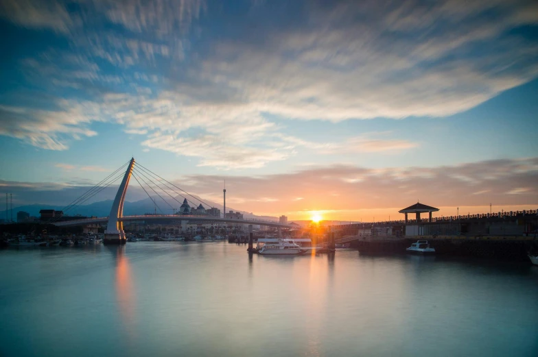 a body of water with a bridge in the background, by Basuki Abdullah, pexels contest winner, hurufiyya, sun rising, harbour in background, taiwan, ultrawide image