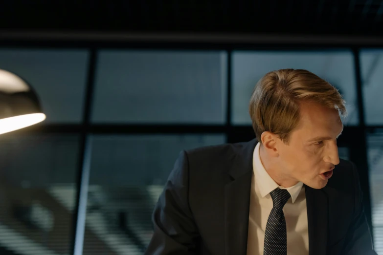 a man in a suit sitting in front of a laptop computer, inspired by David Chipperfield, unsplash, fantastic realism, still from loki ( 2 0 2 1 ), looking at each other mindlessly, johan liebert, 15081959 21121991 01012000 4k