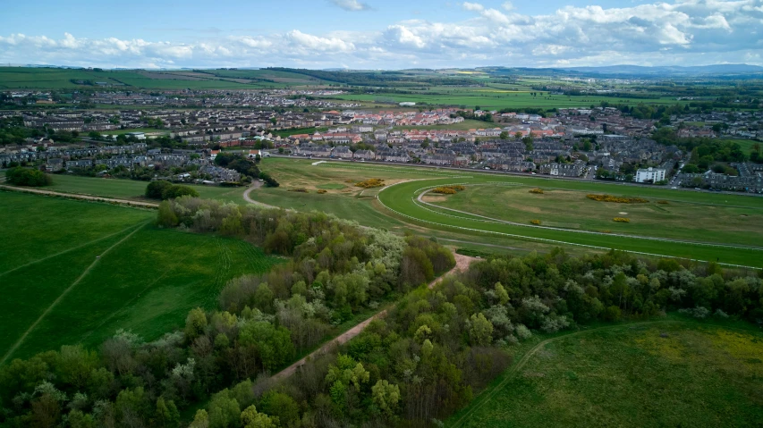 a view of a town from a bird's eye view, by Julian Allen, horse racing, 2022 photograph, edinburgh, an expansive grassy plain