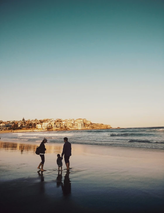 a group of people standing on top of a beach next to the ocean, apartment, profile image, bondi beach in the background, magic hour