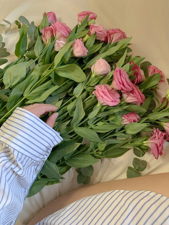 a person laying in bed with a bunch of flowers, by Robbie Trevino, pink tigers, wrapped arms, medium close up, a few roses