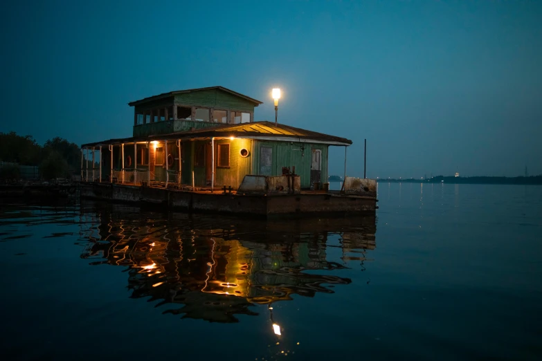 a houseboat floating on top of a lake at night, an album cover, pexels contest winner, humid evening, preserved historical, blues, 2022 photograph