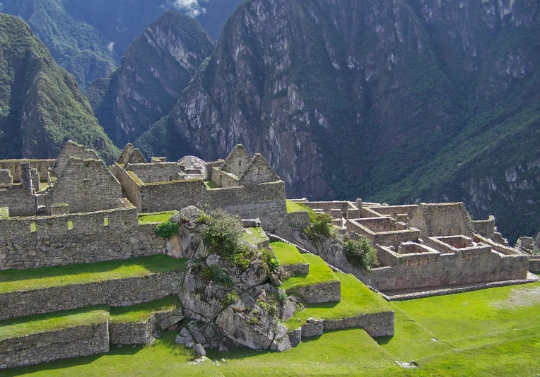 a group of buildings sitting on top of a lush green hillside, pexels contest winner, inca style, avatar image, ruins, grey