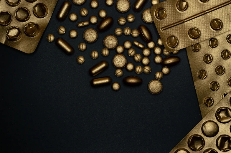 a bunch of gold pills sitting on top of a table, by Emma Andijewska, digital art, black, brown, rectangular, product design shot