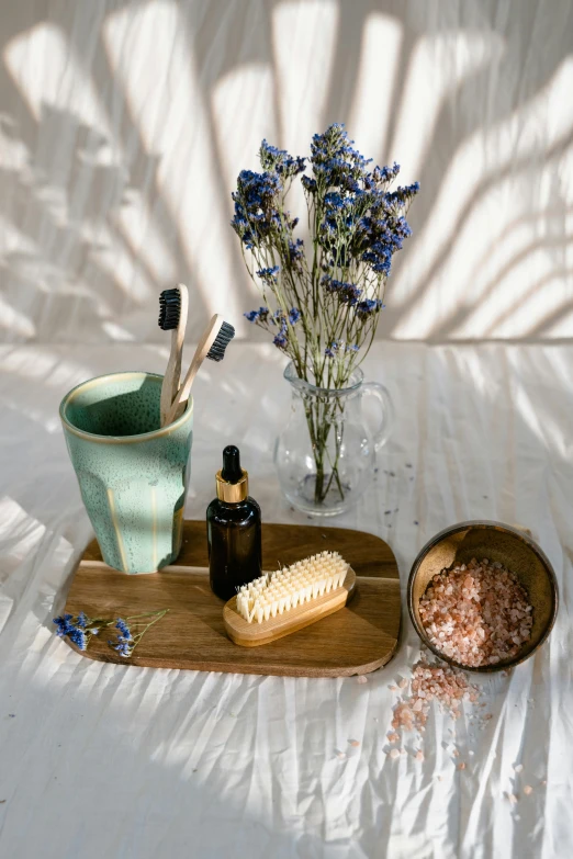 a wooden tray sitting on top of a bed next to a vase of flowers, a still life, inspired by Ceferí Olivé, unsplash, brushes her teeth, with textured hair and skin, dried herbs, on clear background