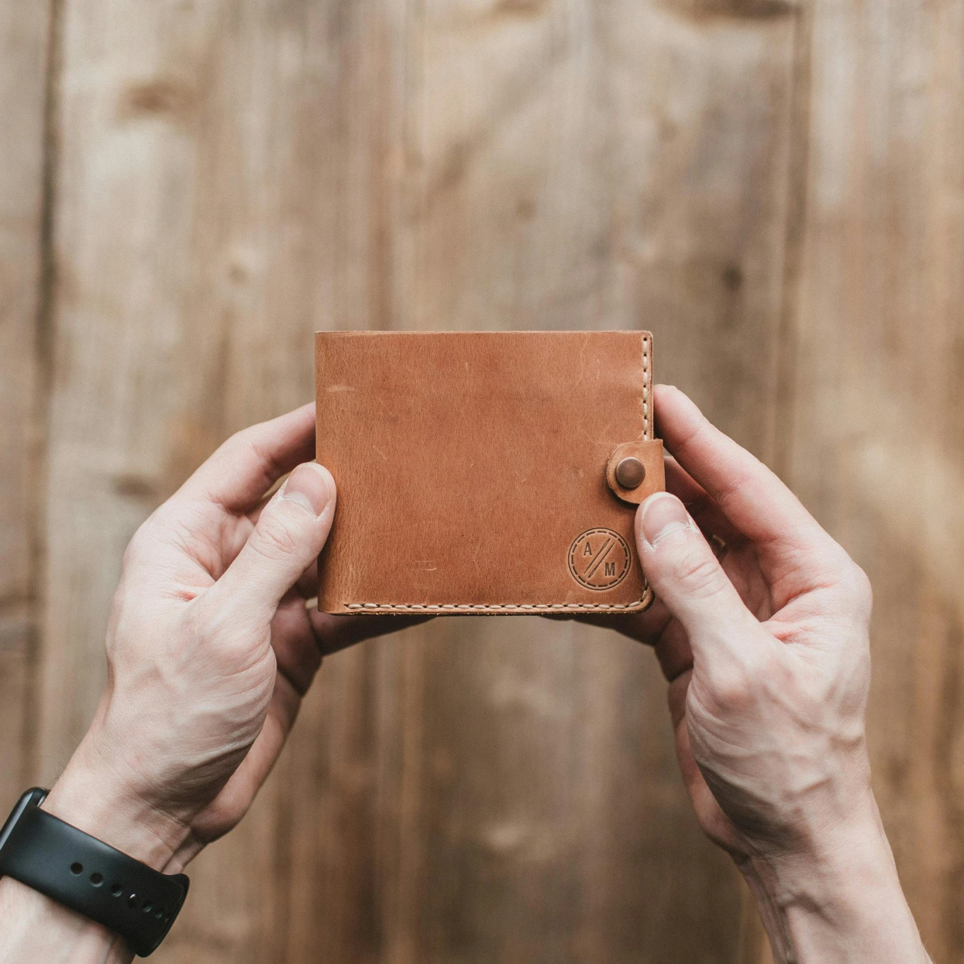 a man holding up a brown leather wallet, by Emma Andijewska, handmade, educational, light tan, extra details