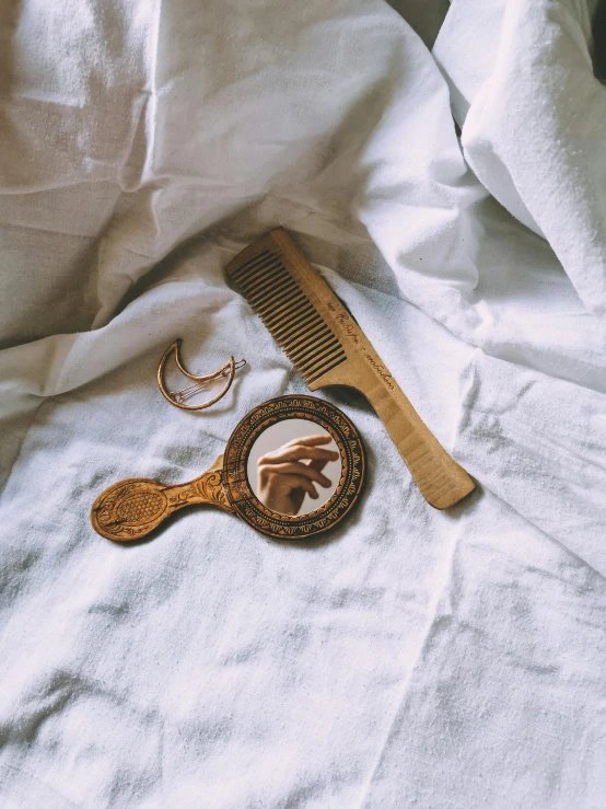 a wooden comb sitting on top of a bed next to a mirror, by Andrée Ruellan, trending on unsplash, renaissance, wears a egyptian ankh necklace, gold gilded circle halo, 1990s photograph, wolves and their treasures