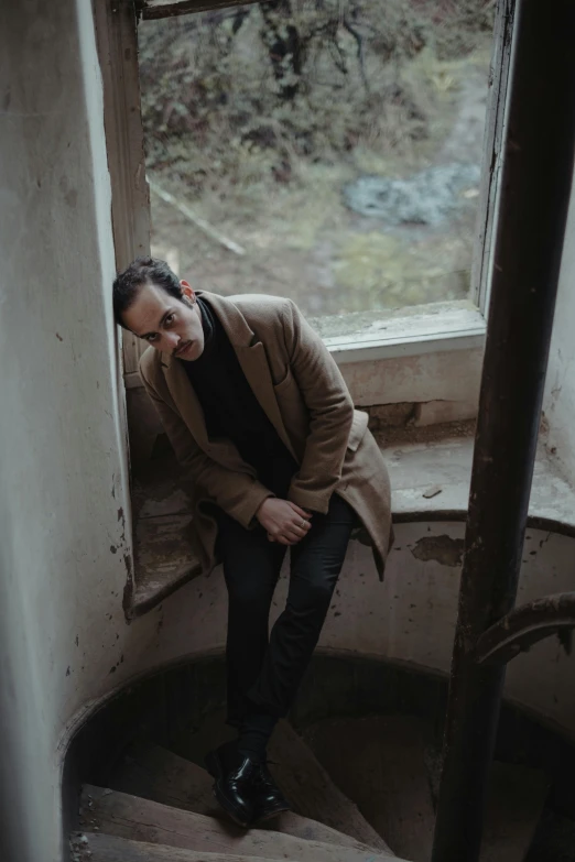 a man sitting on top of a set of stairs, zachary corzine, gloomy mood, looking through a window frame, sitting on a log