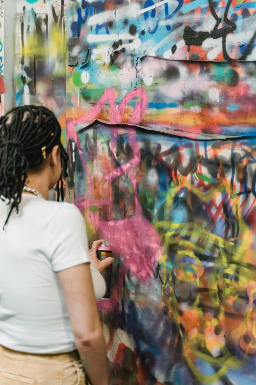 a woman standing in front of a wall covered in graffiti, trending on unsplash, graffiti, rainbow drip paint, tending on art station, taken in the late 2010s, looking from shoulder