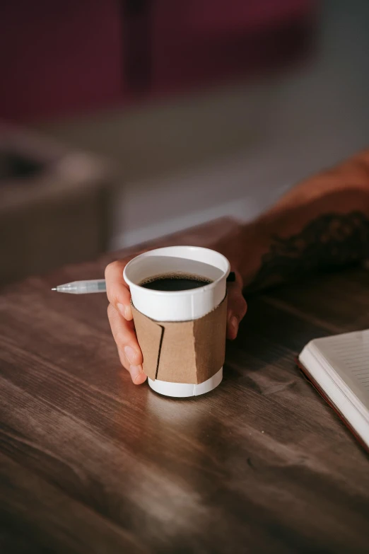 a person sitting at a table with a cup of coffee, trending on pexels, brown paper, no text, holding a stuff, lgbtq