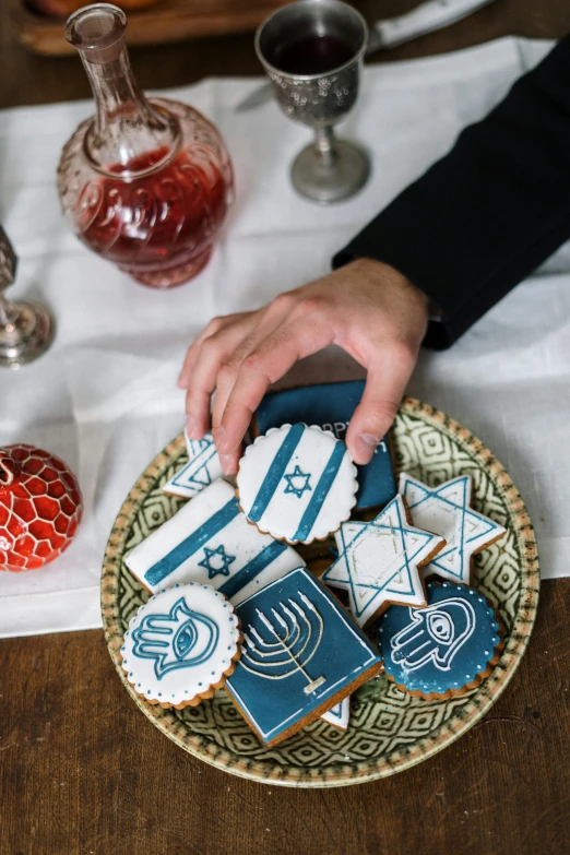 a person sitting at a table with a plate of cookies, hebrew, fully decorated, prussian blue and venetian red, full product shot