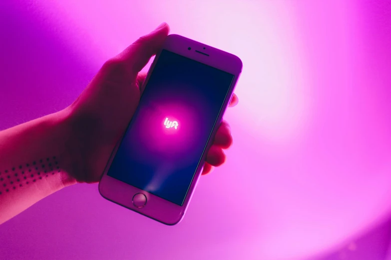 a person holding a cell phone in their hand, a hologram, by Niko Henrichon, trending on unsplash, fuschia leds, karim rashid, ios app icon, bisexual lighting