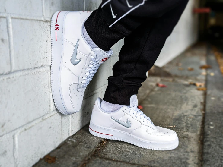 a person standing next to a brick wall, wearing white sneakers, silver white red details, airforce gear, 2263539546]
