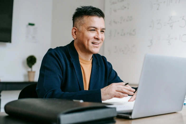 a man sitting in front of a laptop computer, pexels contest winner, temuera morrison, wearing business casual dress, school curriculum expert, allan lee