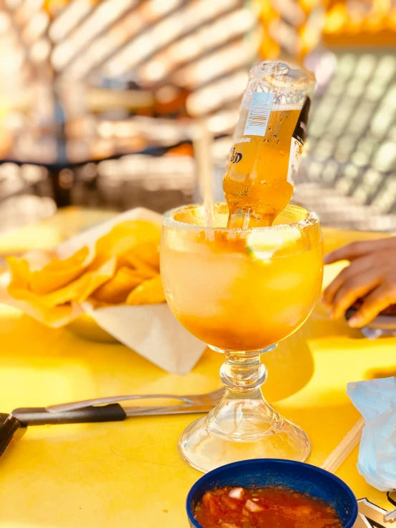 a person sitting at a table with a bowl of food, 🍸🍋, yellow and orange color scheme, sun coast, transparent