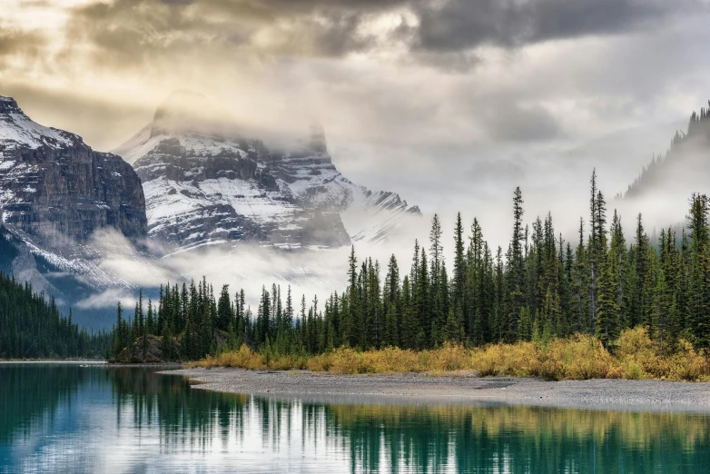 a body of water with mountains in the background, inspired by James Pittendrigh MacGillivray, pexels contest winner, banff national park, conde nast traveler photo, grey forest in the background, national geographics