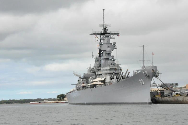 a large battleship sitting on top of a body of water, during the day