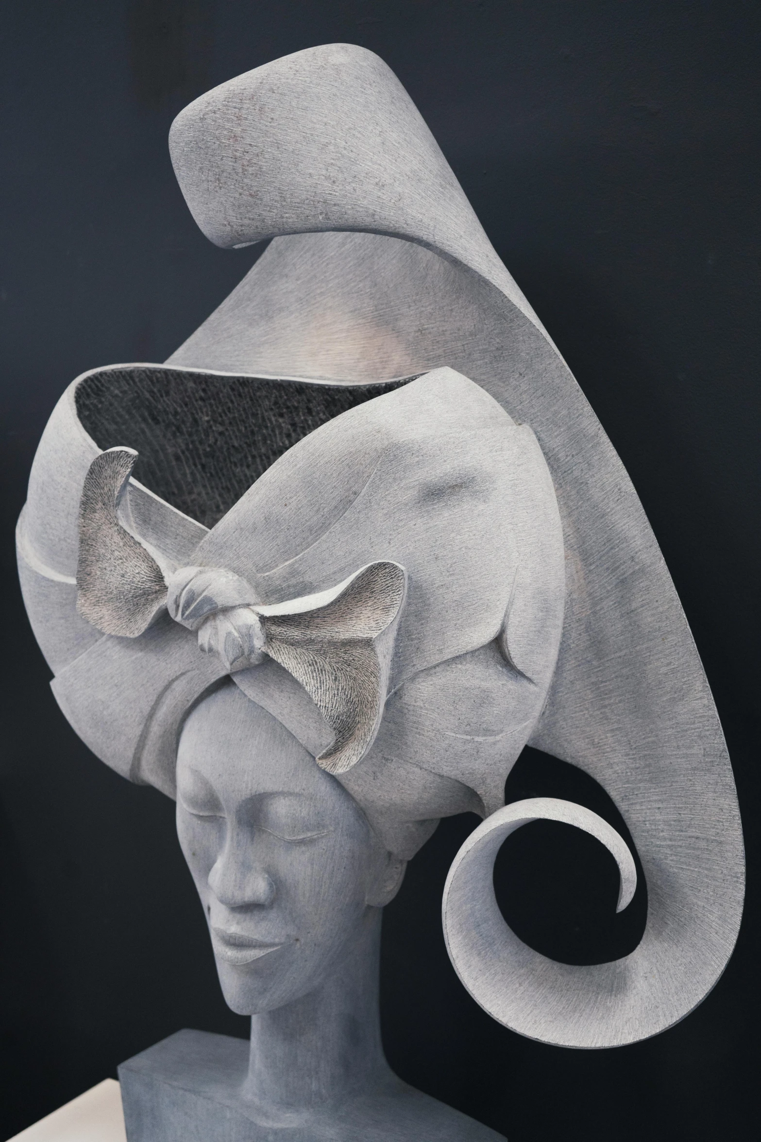 a sculpture of a woman with a hat on her head, inspired by Karel Dujardin, concrete art, ornate and flowing, sepals forming helmet, gray canvas, white witch