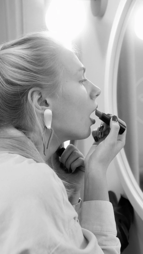 a woman brushing her teeth in front of a mirror, a black and white photo, inspired by Louisa Matthíasdóttir, earring, profile image, square, advanced technology