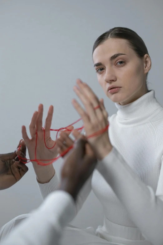 a woman sitting in a chair with her hands in the air, an album cover, inspired by Vanessa Beecroft, trending on pexels, aestheticism, red wires wrap around, marvelous designer substance, close-up of thin soft hand, rope