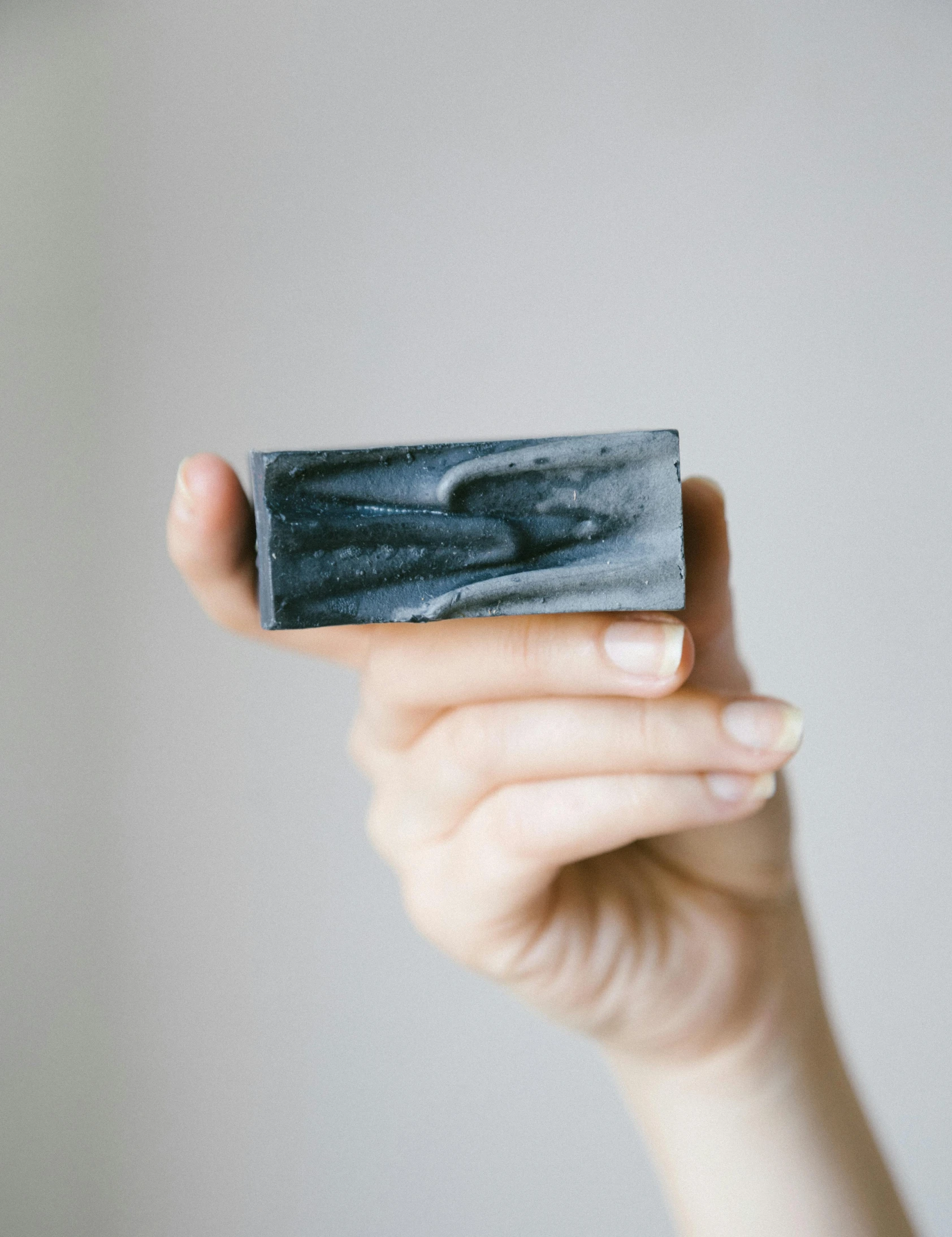 a person holding a soap bar in their hand, by Arabella Rankin, anthracite, dark blue mist, thumbnail, small