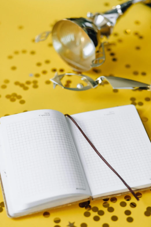 an open notebook sitting on top of a yellow table, new years eve, square glasses, thumbnail, less detailing